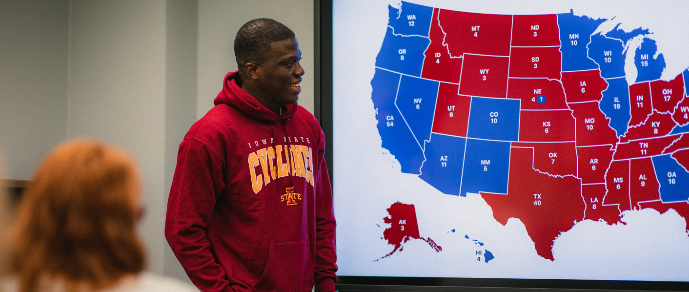 A student stands in front of a map of the United States